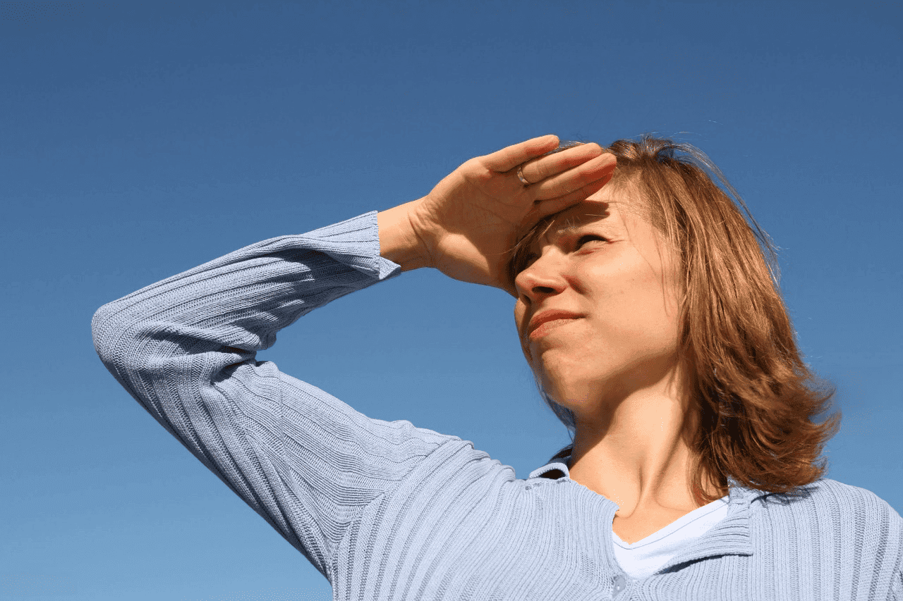 Mulher protegendo os olhos do sol, evidenciando a importância da proteção ocular contra raios UV. Saiba mais na Oftalmo Day.
