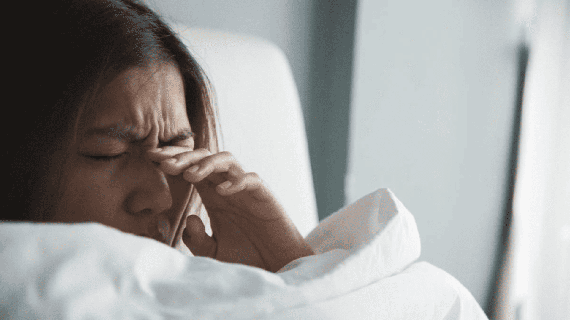 Mulher esfregando os olhos ao acordar, com visão embaçada